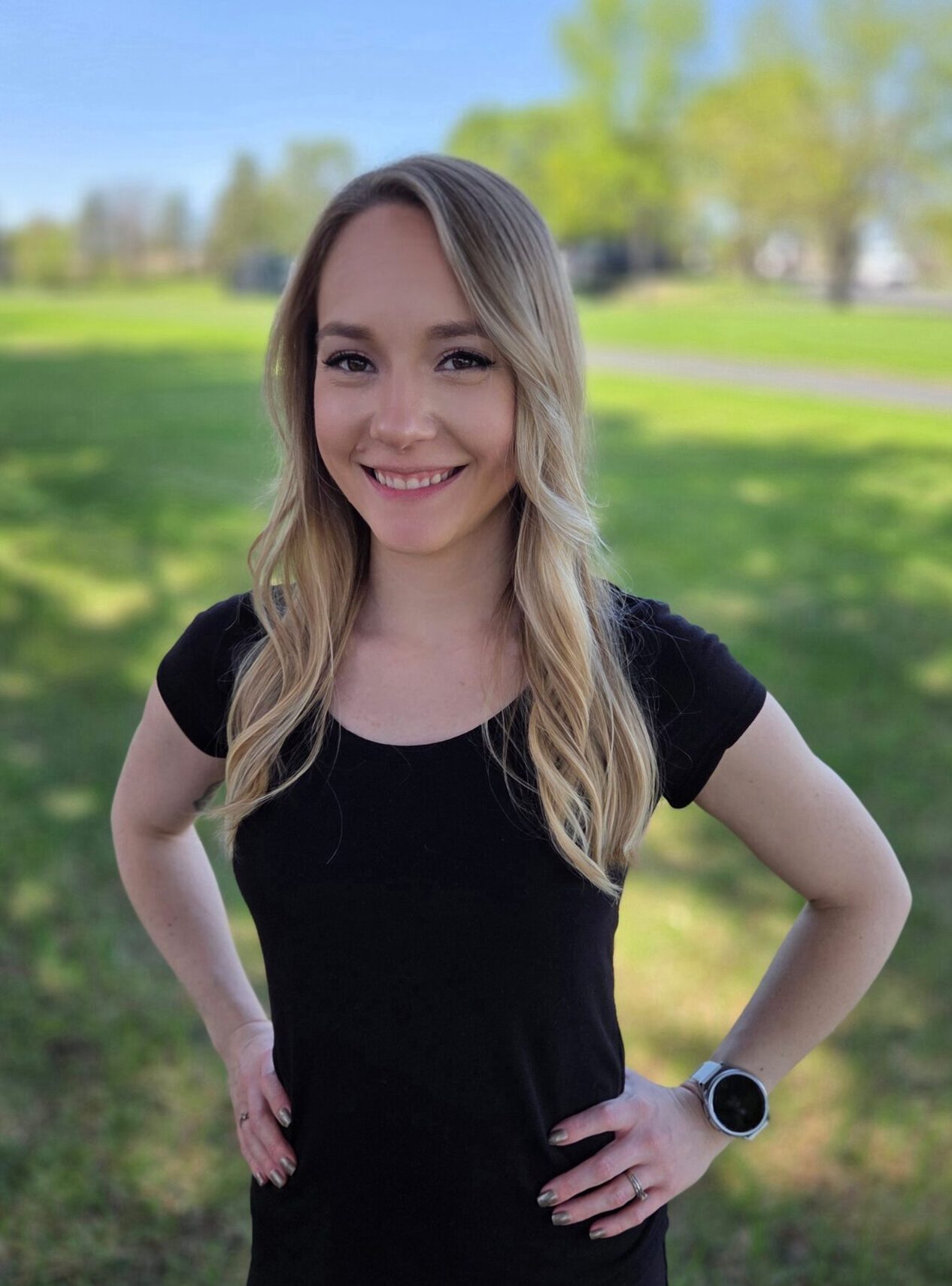 Smiling woman standing in a green park.