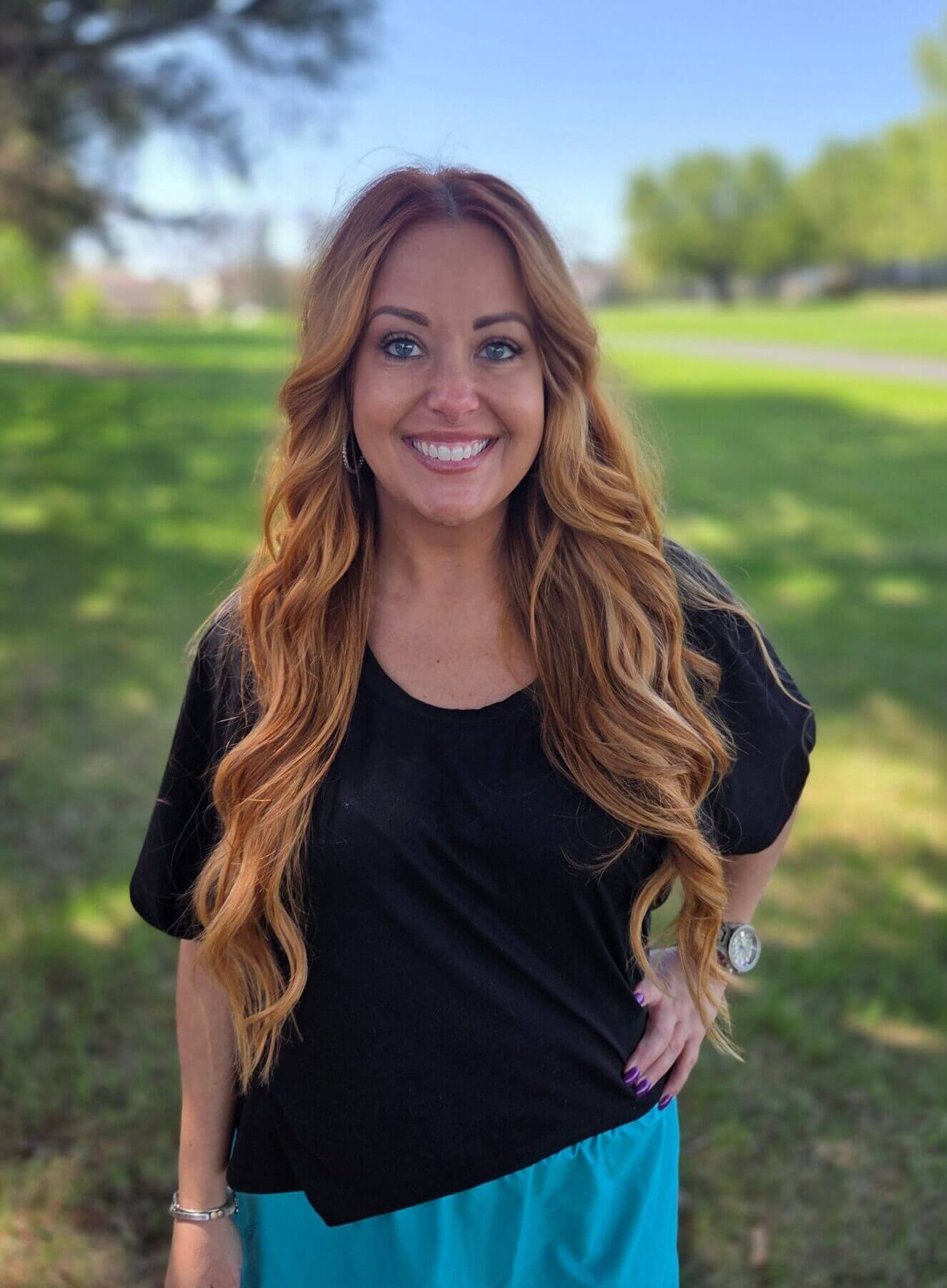 Smiling woman standing in a park.